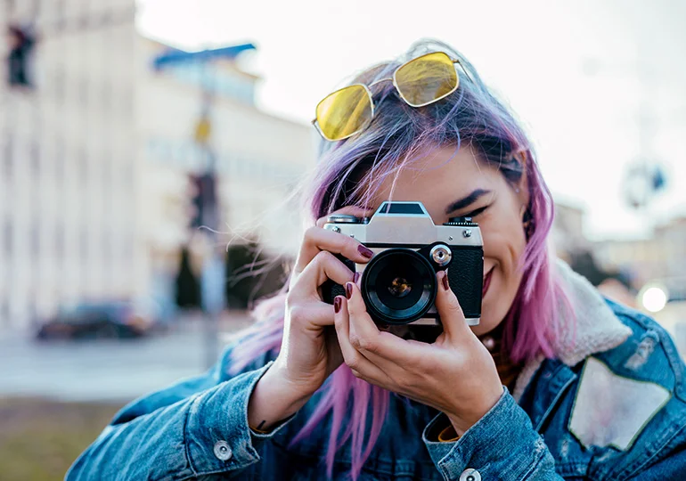A young person holding up a camera taking a photo for the Feel Out Loud Community Creator Space at Kids Help Phone
