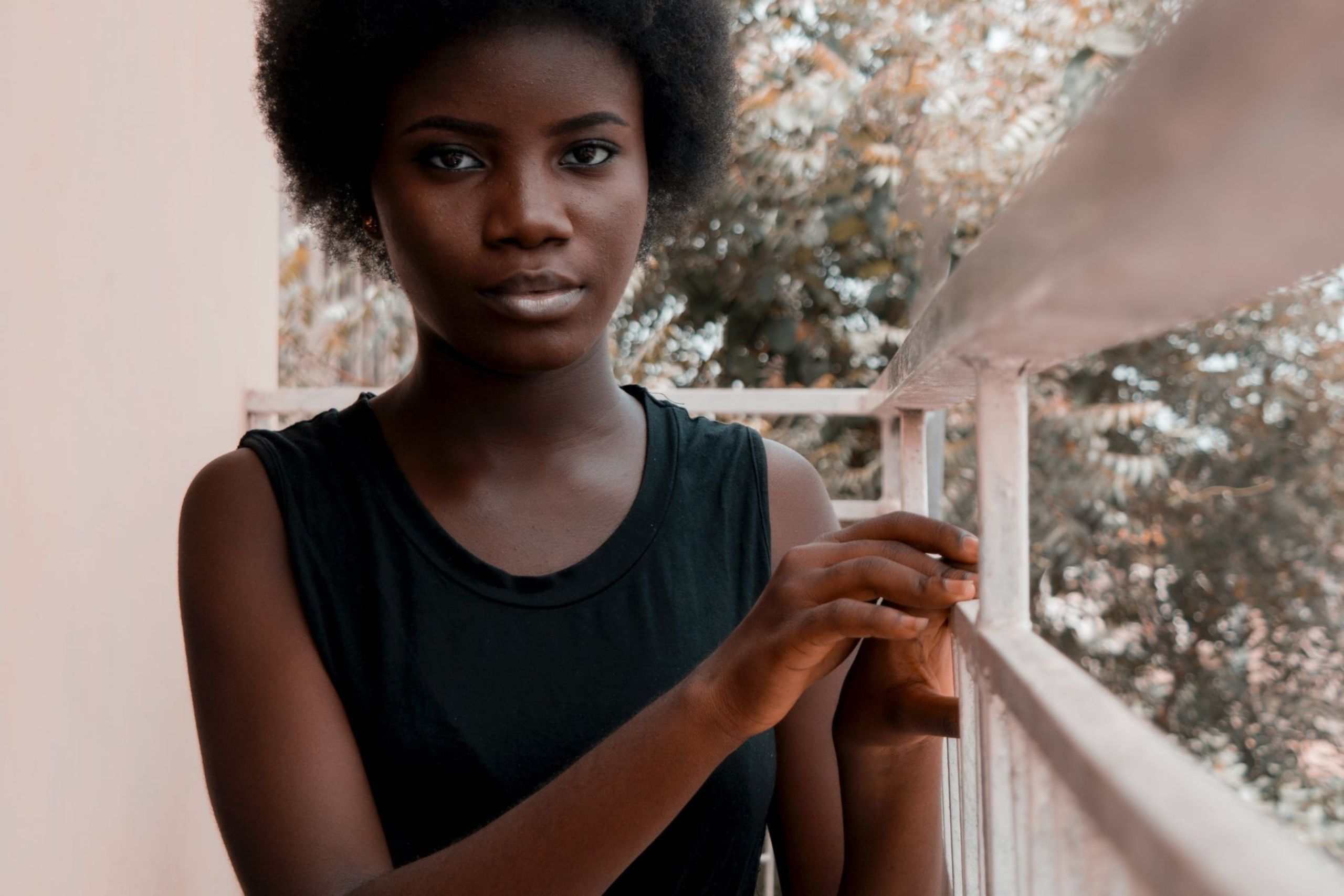 A young person outside directly facing the camera, with trees blurred in the background.