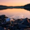 Lightbulb on top of rocks next to a lake at sunset