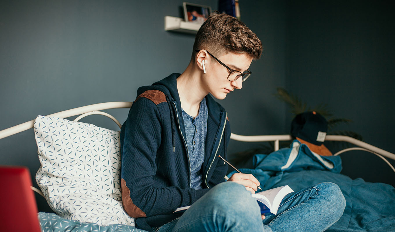 Community creator sitting on a bed while writing in a notebook
